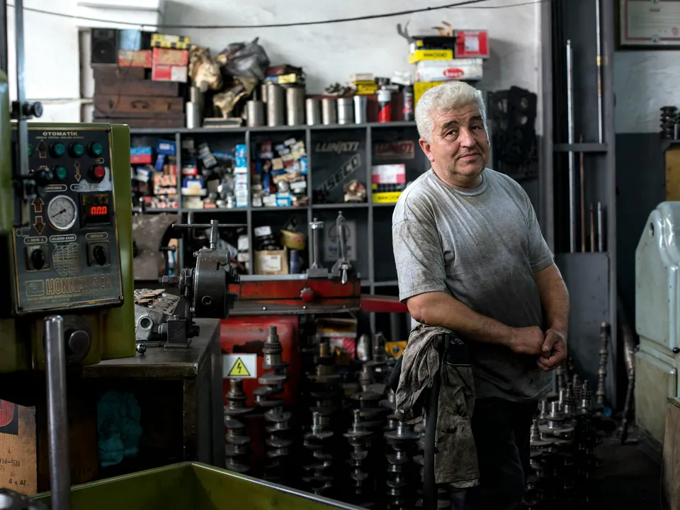 An engineer standing in his machine shop among lathes, tools and parts